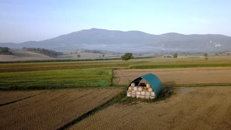 shed with rolls of hay on the tuscan countryside near florence, italy, aerial pan-left reveal shot