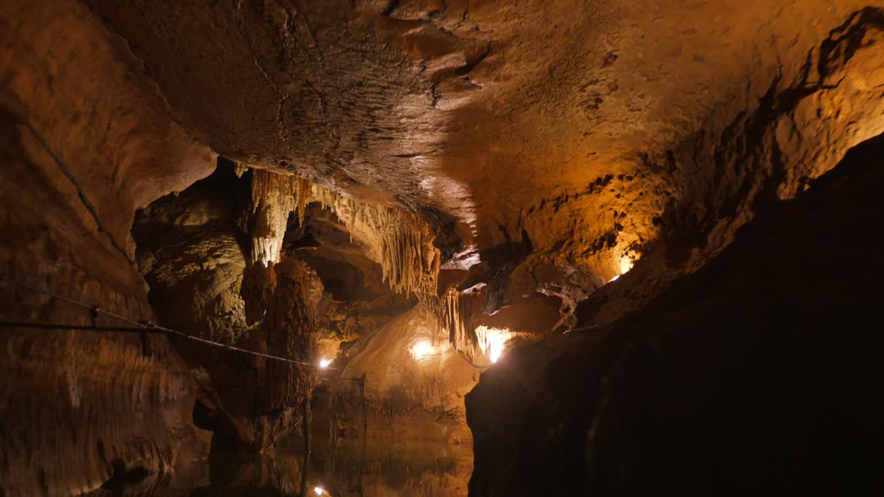 Journey through a beautifully lit cave showcasing dramatic rock formations and stalactites