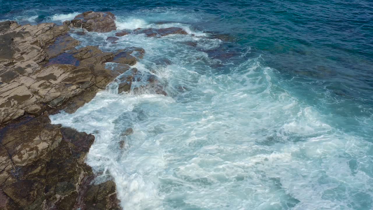 toma de drones de olas rebotando en las rocas en la playa