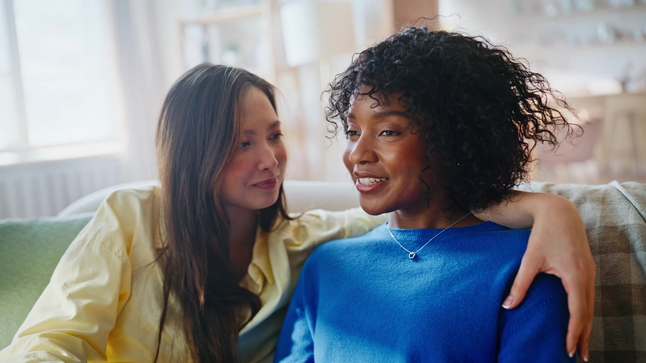 Lesbian couple holding hands sofa. Closeup affectionate women bonding home.
