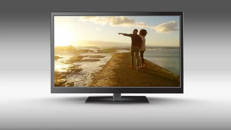 flat screen tv with a couple at the beach on its screen