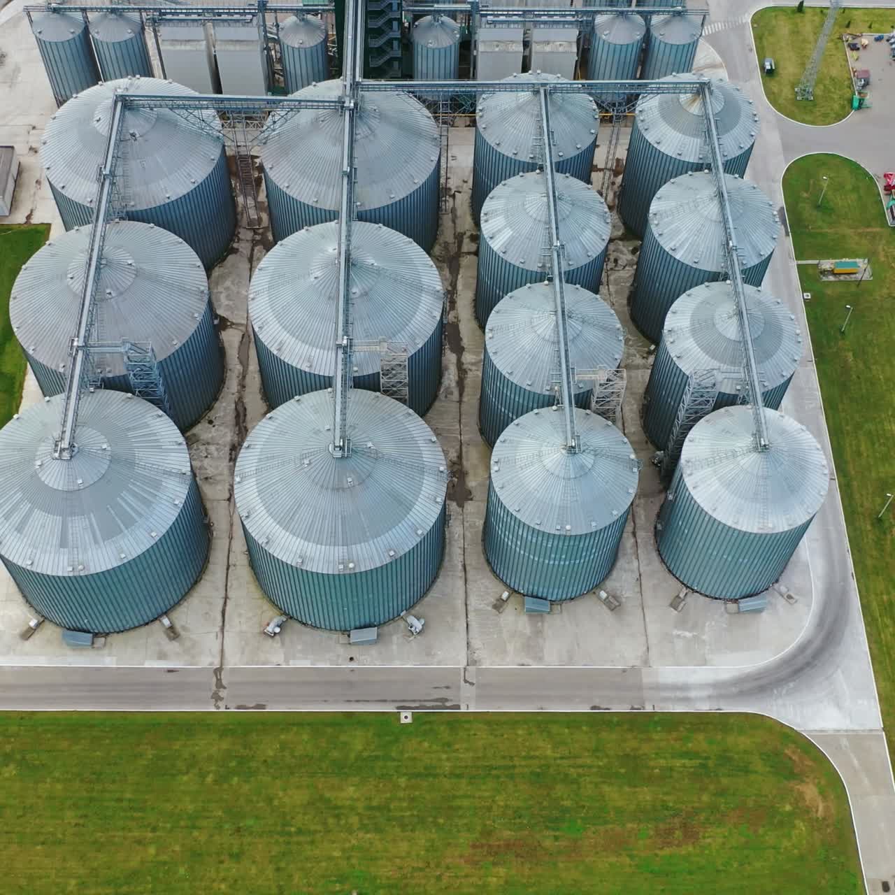 Large steel elevators. Granaries for grain on the field. Silver silos on agricultural factory. View from above.