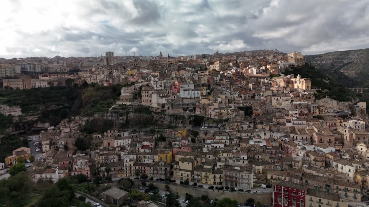 Vista aerea panoramica di una storica città collinare sotto un cielo nuvoloso