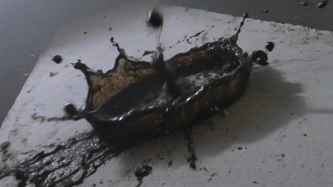Glóbulo caindo espirrando material escuro em anel em prateleira de gesso no quarto, espalhando fragmentos.
