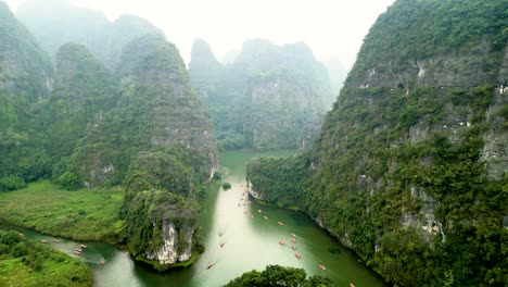 aerial view of tourists on boat exploring trang an by the river along limestone rock formations in ninh binh, vietnam.