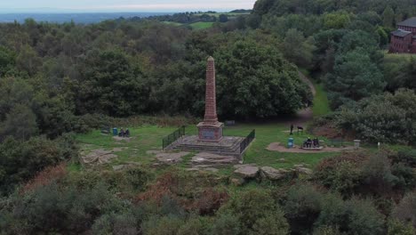 Aerial-view-sandstone-obelisk-war-memorial-Frodsham-hill-overlooking-Cheshire-Liverpool-skyline-orbit-left