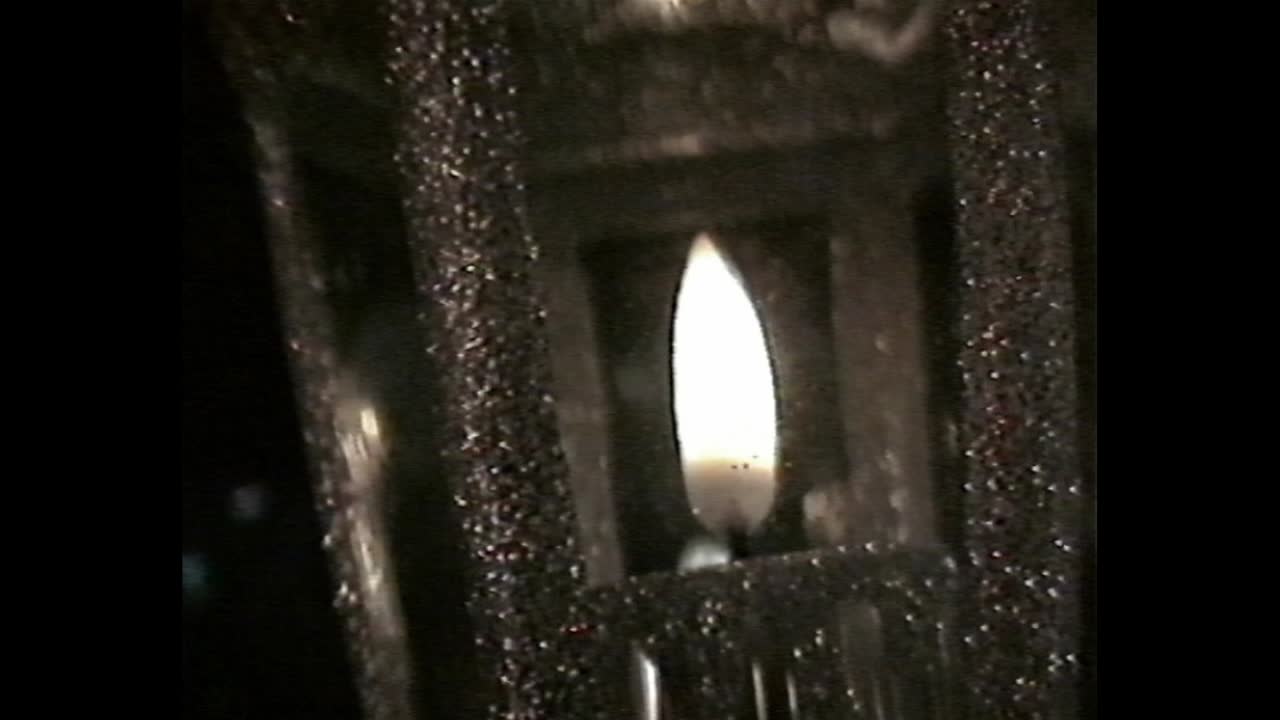 Close-up of candle inside lantern with VHS grain
