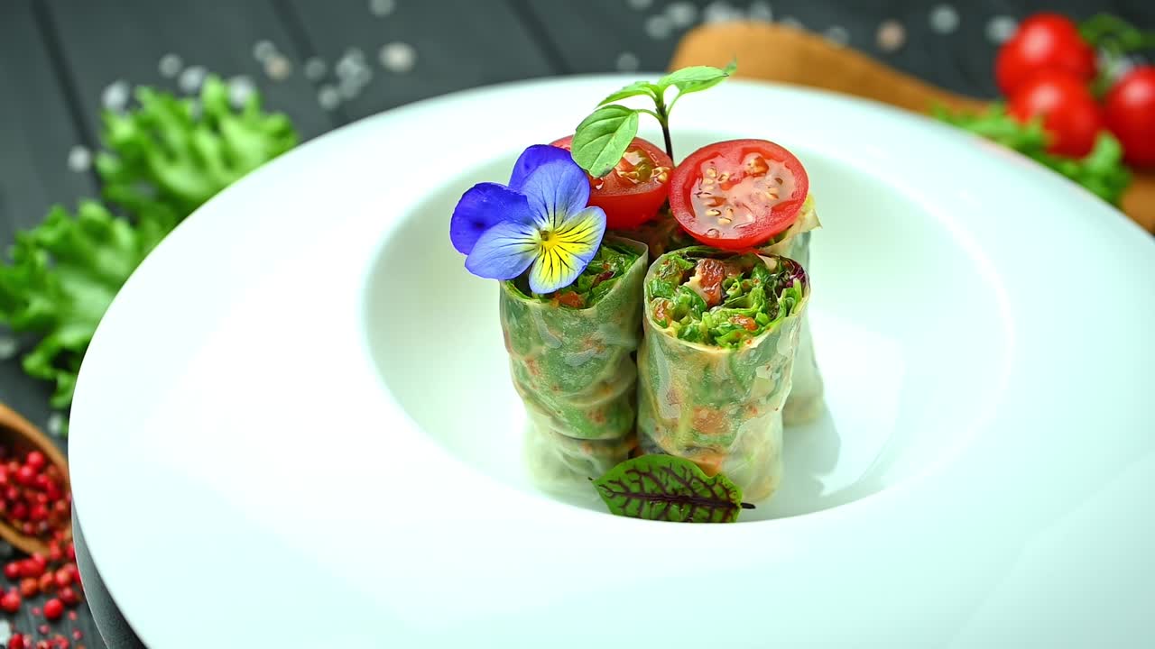 Rollitos de primavera frescos con tomates y hierbas en un plato blanco. Los rollitos de primavera frescos se colocan en un plato blanco con tomates y hierbas dispuestas encima.