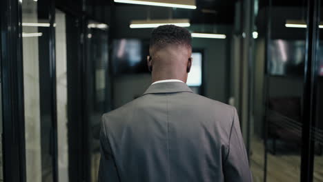 the camera follows the back of a man walking down the corridor of a business center