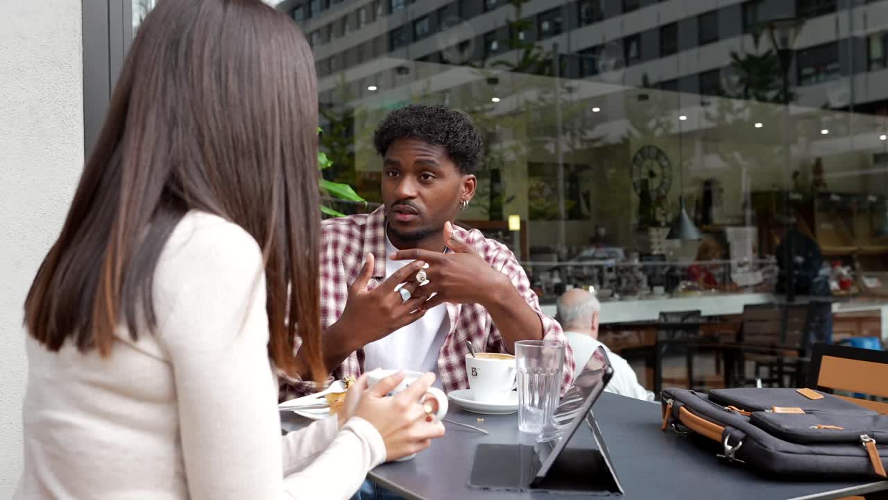 Young Man and Woman Having a Conversation at an Outdoor Cafe
