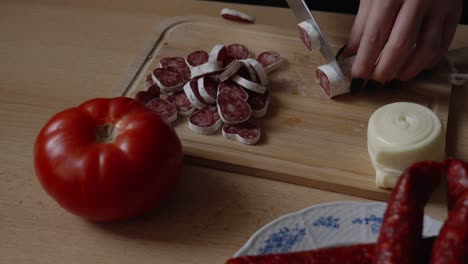 fuet salami being sliced in the kitchen, woman preparing food, rustic atmosphere, close-up