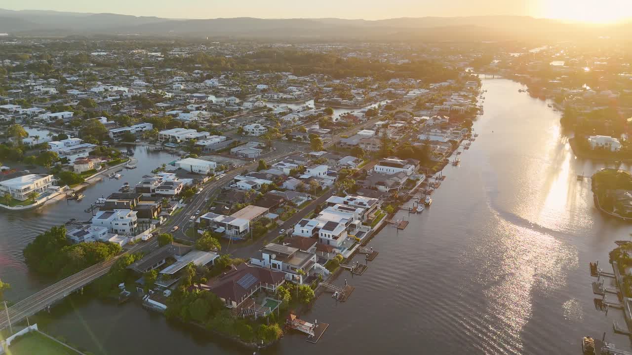 Drone captures serene sunset over Nerang River, showcasing Gold Coast's urban landscape with warm, golden lighting
