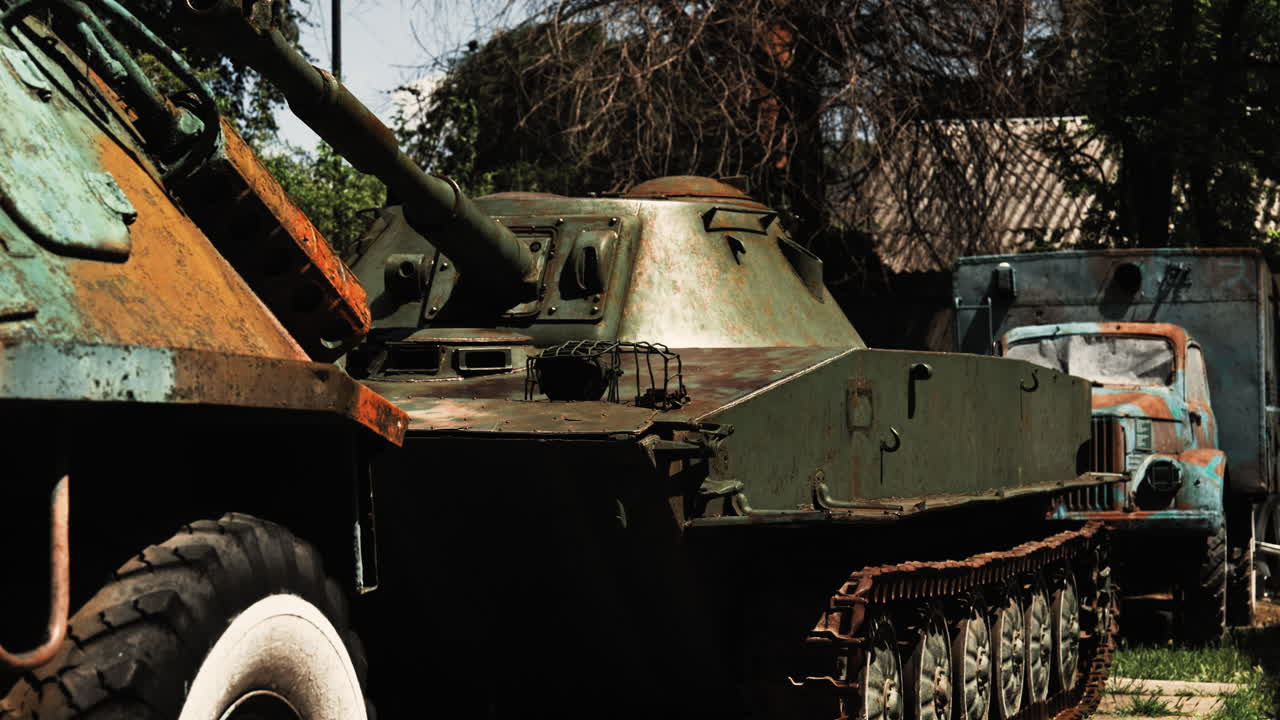 Rusted World War II-era Soviet tank on display outdoors, surrounded by convoy vehicles at a historic military site in Chișinău, Moldova. A glimpse into wartime history and equipment.