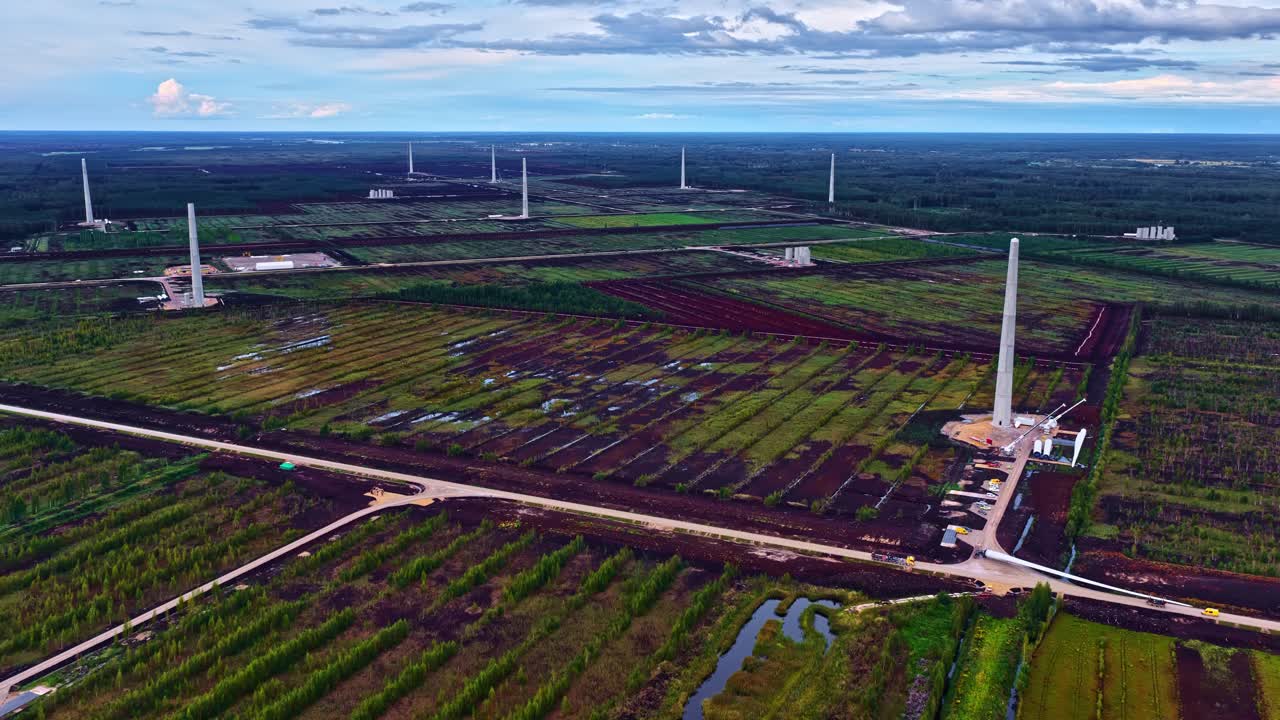 Drone overview of patchwork of colorful farm fields and small roads connecting oil flare stacks between agriculture land in bright daylight