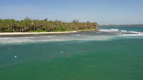 vuelo en órbita aérea por encima de un grupo de surfistas rompiendo el oleaje de indonesia