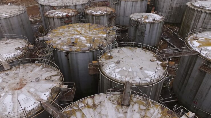Sorvolo di droni su serbatoi di carburante corrosi in una zona industriale in decadimento, Lettonia
