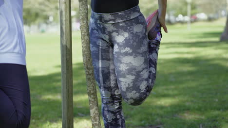 Closeup-shot-of-young-and-senior-women-stretching-legs-in-park.