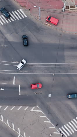 aerial top view of traffic cars driving on road intersection crossing. elevated view downtown street of day. vertical video