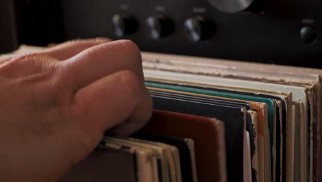 cerrar las manos del hombre hojeando discos de vinilo antiguos en casa