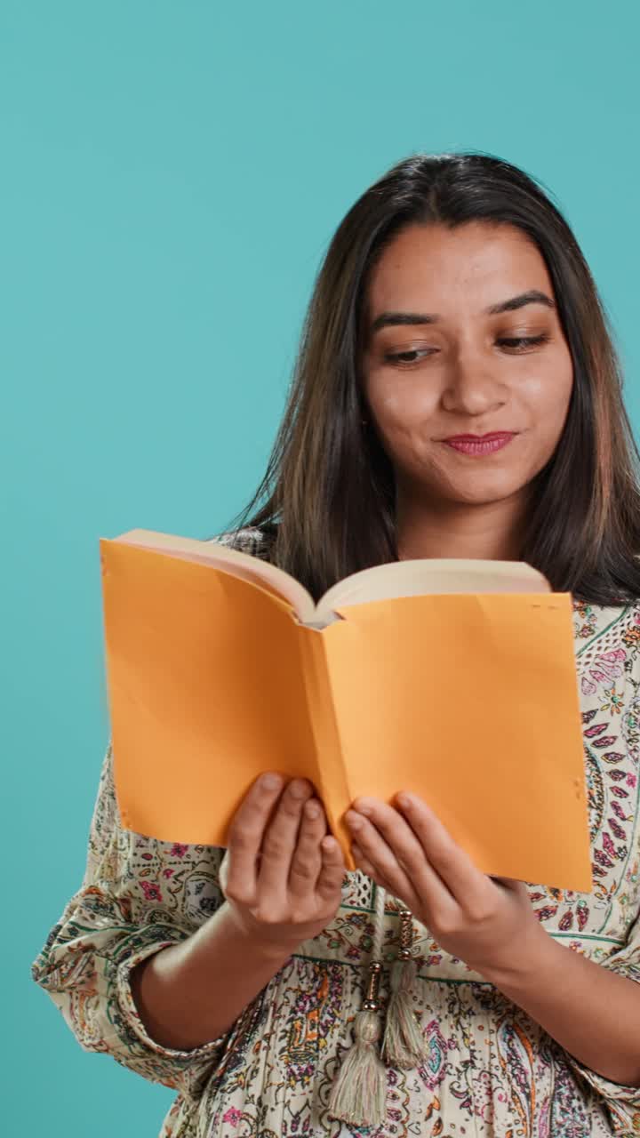Giovane donna indiana che legge un libro con espressione sorpresa e felice