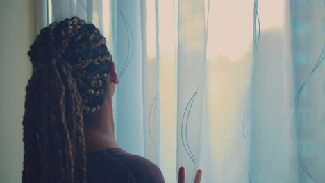 young mixed race woman opening room curtains on window on sunny summer morning