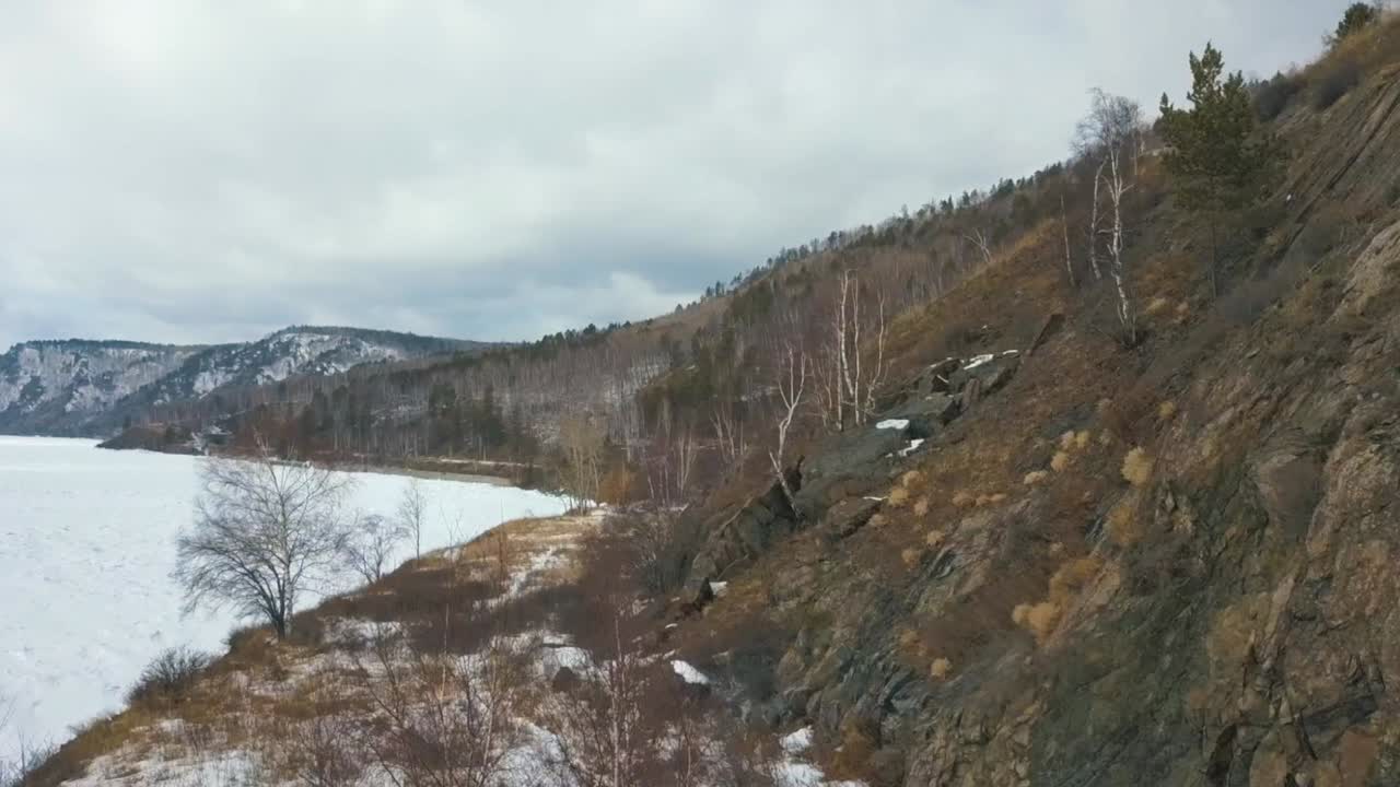 paisaje de invierno de un lago congelado y costa rocosa