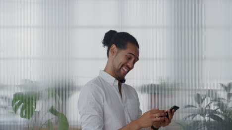 Retrato-Feliz-Joven-Empresario-Hispano-Usando-Un-Teléfono-Inteligente-Disfrutando-Leyendo-Mensajes-En-Línea-Enviando-Mensajes-De-Texto-En-Un-Teléfono-Móvil-Riéndose-Compartiendo-Comunicación-En-Cámara-Lenta