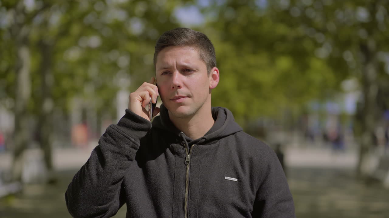 밖에서 스마트폰으로 이야기하는 심각한 남자