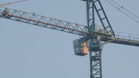 a close-up of a high-rise building under construction, with visible concrete structures and scaffolding, beside a crane, captured at dusk