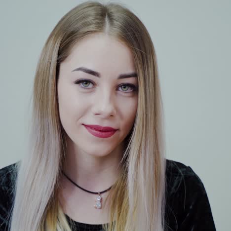portrait of a beautiful girl with perfect make-up. blonde woman with long hair looking on camera and smiling on grey studio background.