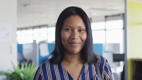retrato de una mujer de negocios afroamericana mirando a la cámara y sonriendo en la oficina, cámara lenta