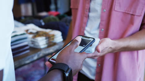 mujer en una tienda de ropa haciendo pago sin contacto con una aplicación en su teléfono móvil