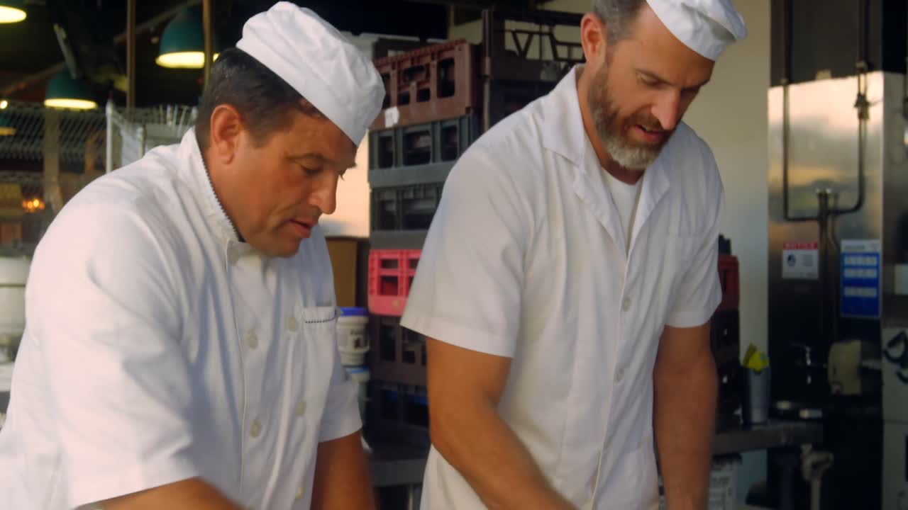 cocineros amasan la masa de la pizza en la mesa de harina 4k