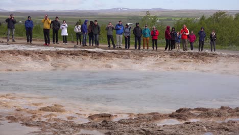 strokkur geyser erupts in front of tourists in iceland