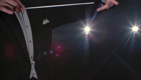 moving hands of an orchestra conductor directing musicians with movement of baton on black background with lights. conducting, directing classical musical performance with visible gestures. close up