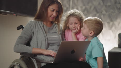 mujer muestra a los niños pequeños videos divertidos en una computadora portátil moderna