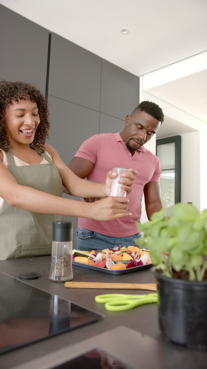 Vertical video: Seasoning vegetables, couple preparing meal together in modern kitchen