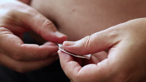 close up of cleaning the abdomen with a wet hygiene wipe in preparation to self apply medicine through a medical needle pen injecting the substance in a fatty area of the belly