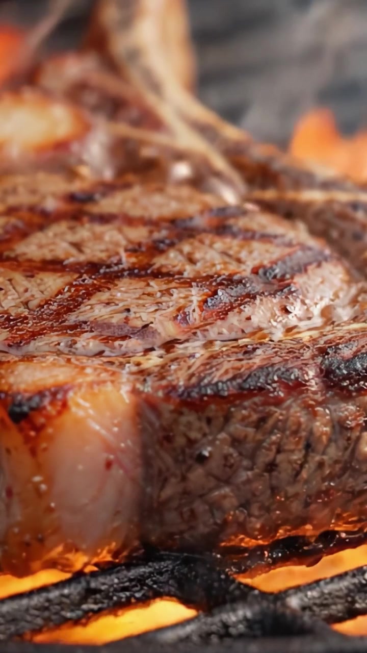 Sizzling Perfection: A Close-Up of Juicy Steak Grilling Over Flames, Highlighting the Crispy Char and Tender Meat Juices in the Heat of Cooking.