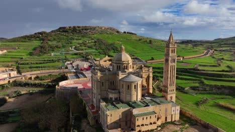 은 날 에 바실리카 타 피누 (basilica ta' pinu) 를 공중 에서 볼 수 있으며, 그 배경 에는 초록색  이 있다.