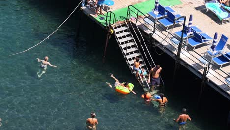 people swimming and relaxing by the pier