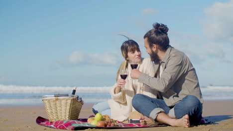 young caucasian couple drinking red wine at seashore