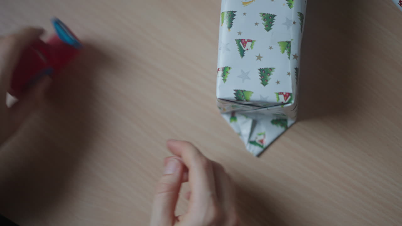 Party organizer, tightly wrapping the gift box with decorative paper and cello tape