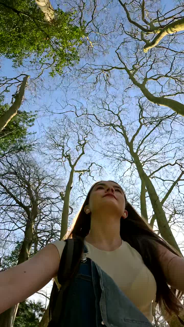 Woman looking up at trees in sunlight