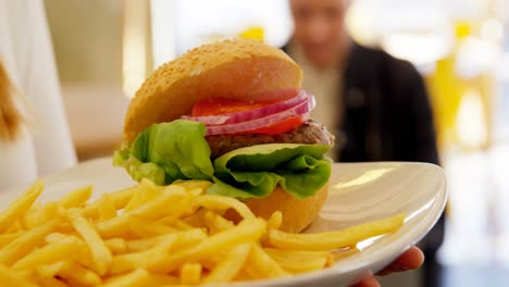 Mid-section-of-waitress-holding-junk-food-in-tray-4k