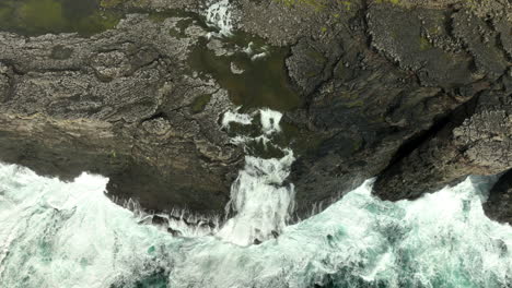 aerial birdseye over sea waters, tilt up revealing lake sorvágsvatn, faroe islands