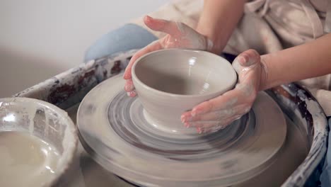 woman making a bowl on a pottery wheel