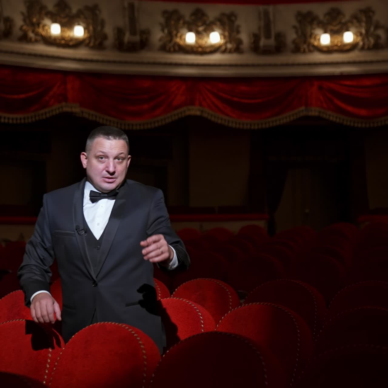 Disappointed actor in empty theatrical hall. Man in costume standing among vacant red seats and calling someone. No audience in opera house. Pandemic in the world