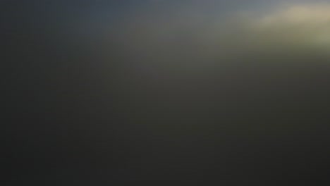 drone shot of an incredible landscape covered under the fog with surrounding mountains in the morning at winter time in slovenia captured in 4k, drone going above the fog