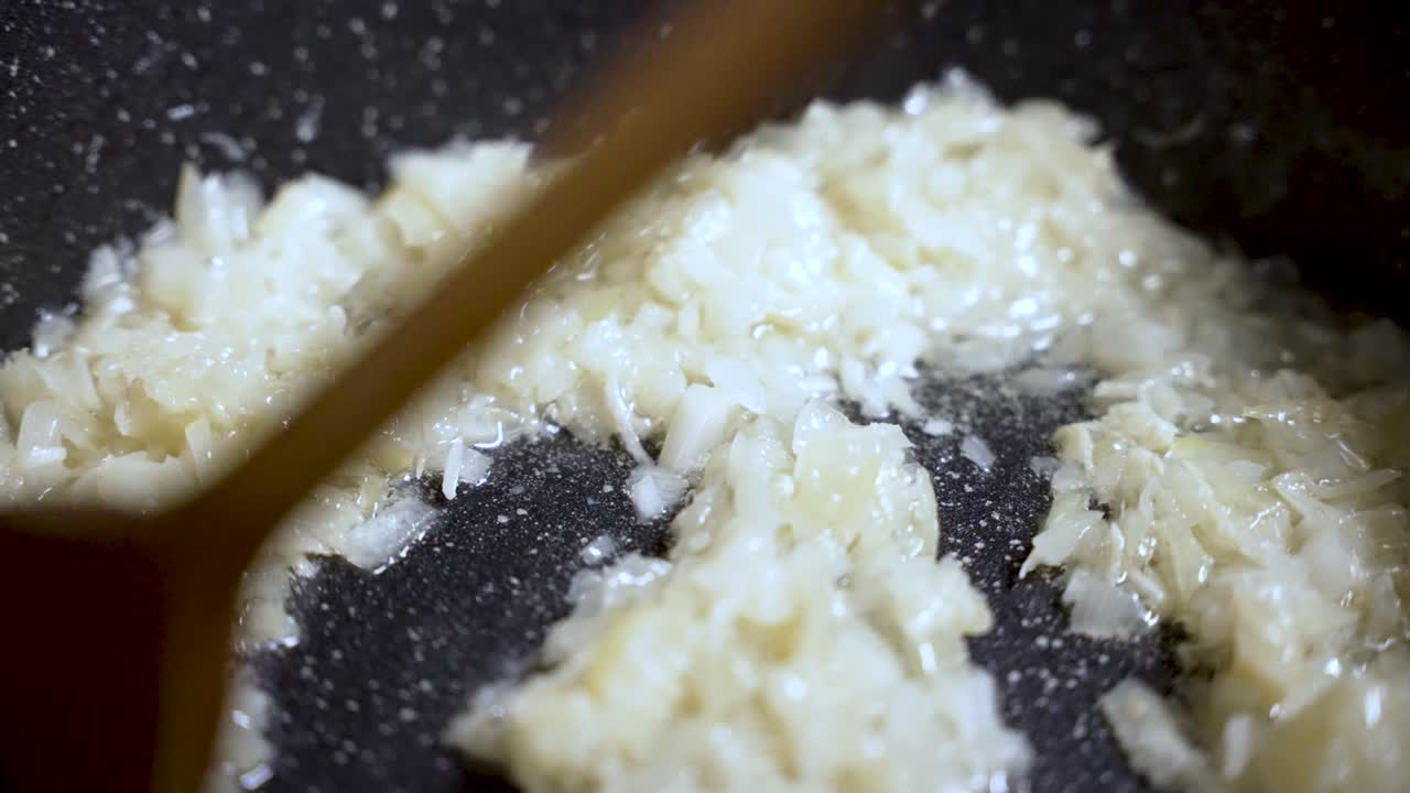 Chopped white onions are browning in hot oil in a pan, creating a flavorful base for a delicious culinary creation